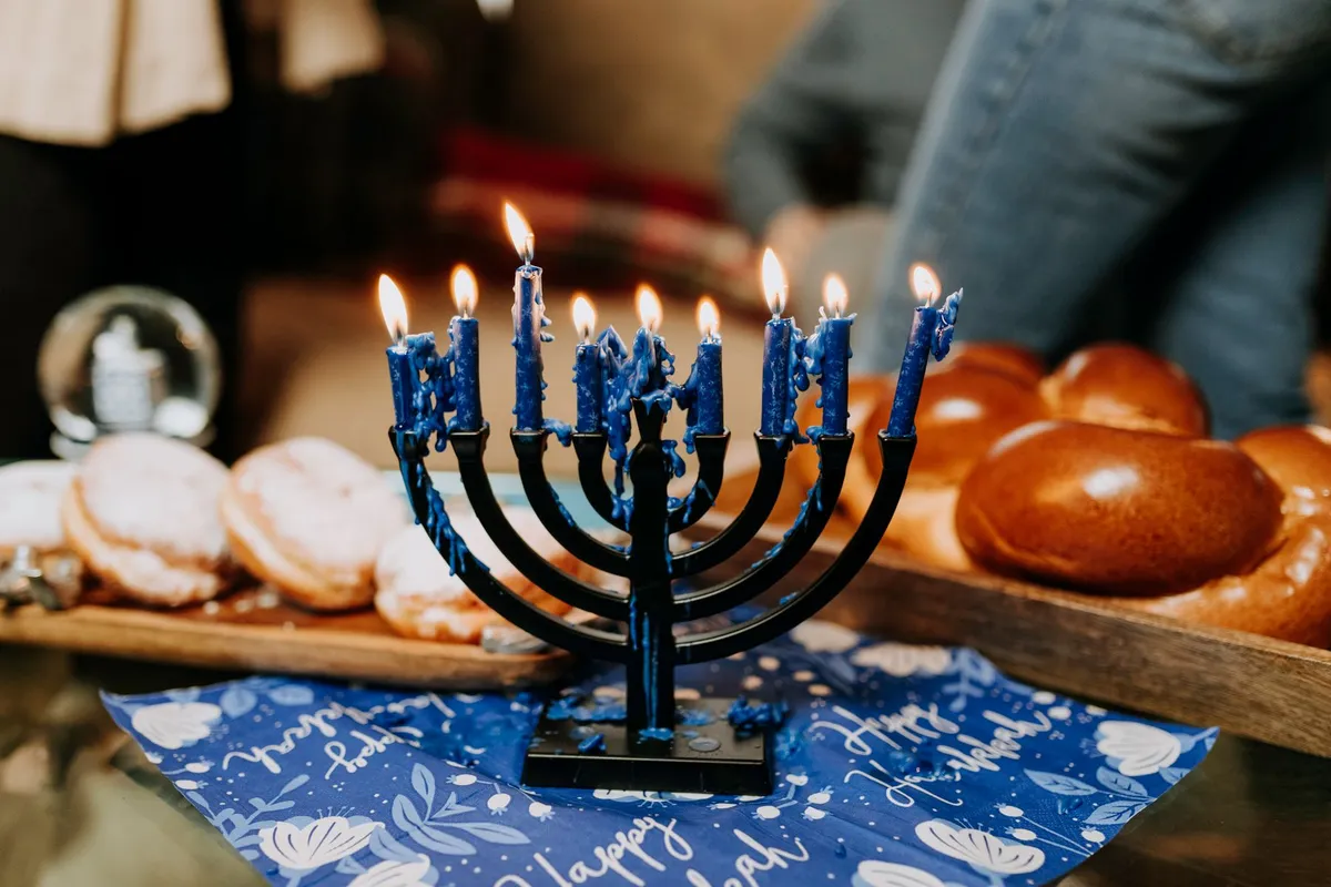 Illustration: a lit menorah on a table with doughnuts