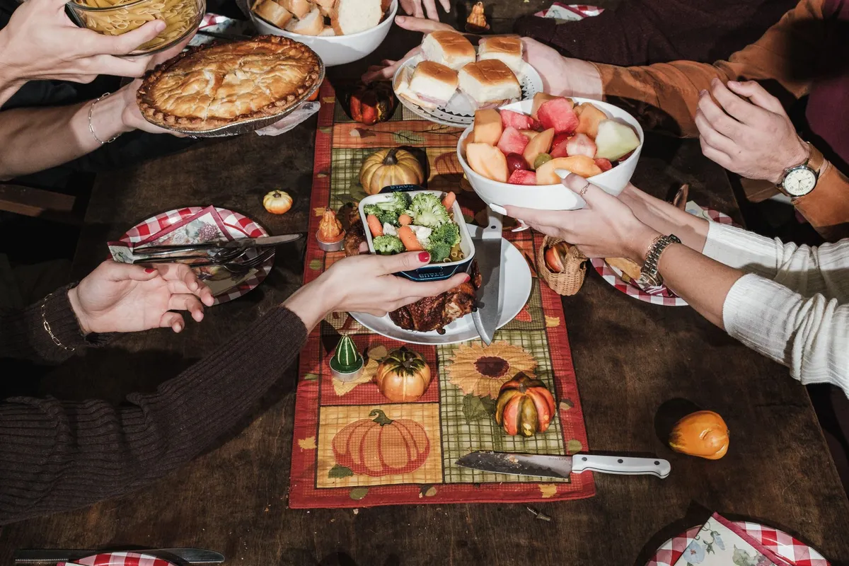 Illustration: hands passing dishes across a Thanksgiving table